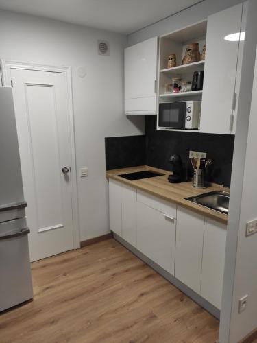 a kitchen with white cabinets and a wooden floor at El Ático de la Estación in Oviedo