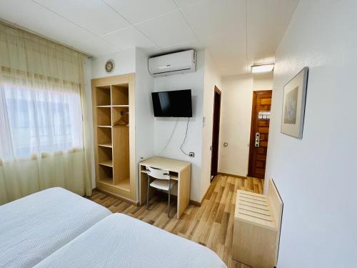 a bedroom with a bed and a desk and a television at Tortosa Parc in Tortosa