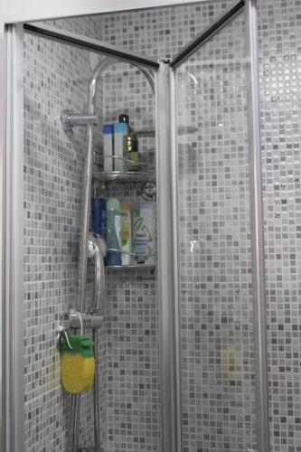um chuveiro na casa de banho com paredes em azulejos brancos em Red Apartment em Sarajevo