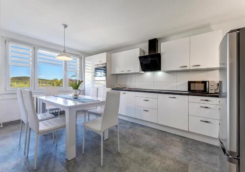 a kitchen with white cabinets and a table with chairs at Haus N°9 in Hohendorf