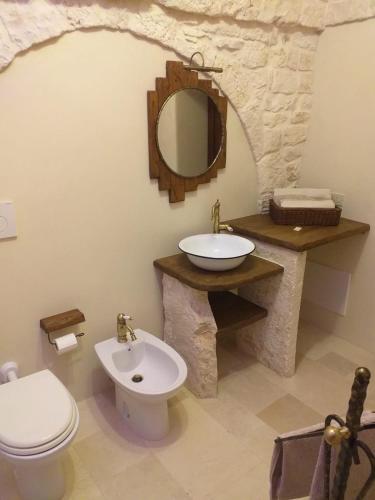 a bathroom with a sink and a toilet and a mirror at Trulli: La pace dei sensi in Alberobello