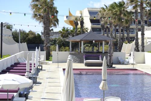 une piscine avec des chaises et des parasols à côté d'un hôtel dans l'établissement Studio Naturiste Adam Résidence Le Jardin D'Eden, au Cap d'Agde