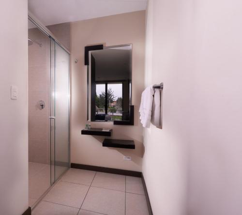 a bathroom with a shower and a sink and a mirror at Venue Hotel in Cuenca