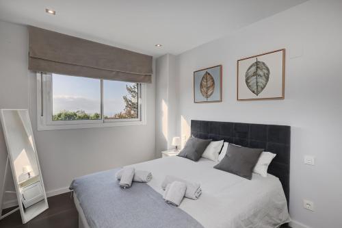 a bedroom with a large bed with two windows at Brand new apartment with pool and SEA VIEW in Marbella in Marbella