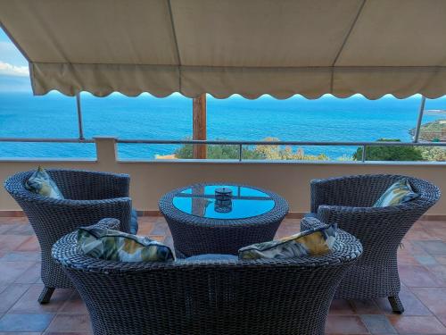a patio with chairs and a table with a view of the ocean at Golden Sunrise - Nikos Home in Gythio