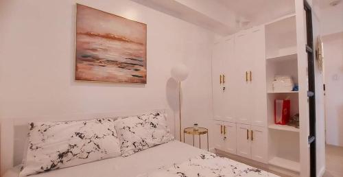 バコロドにあるEcostay @ Amaiaのベッドルーム1室(ベッド1台付)が備わります。壁には絵画が飾られています。