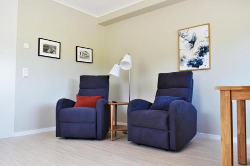 two blue chairs and a lamp in a living room at Närebo Gårdshotell & Restaurang in Lidköping