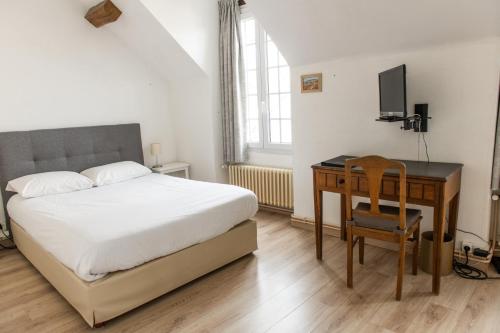 a bedroom with a bed and a desk with a computer at Le Relais Des Templiers in Beaugency