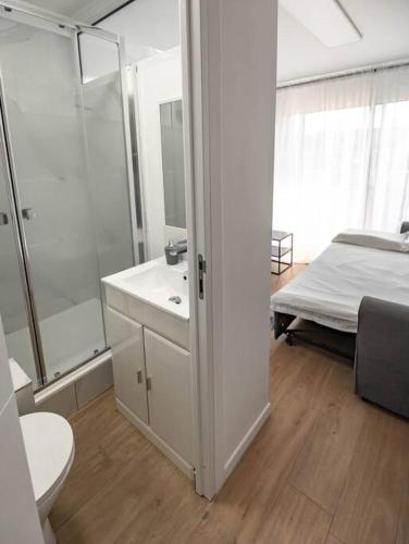 uma casa de banho branca com um chuveiro e uma cama em Studio / 900m de la plage em Fréjus