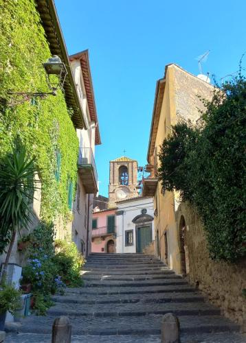 an alley with stairs leading to a building with a clock tower at Il Loft del Lago in Anguillara Sabazia