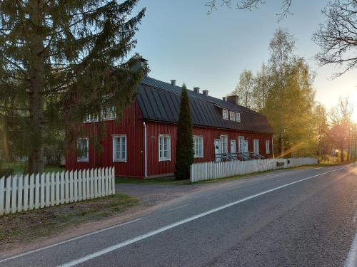 a red house with a white fence next to a road at Matildan Riihi in Mathildedal