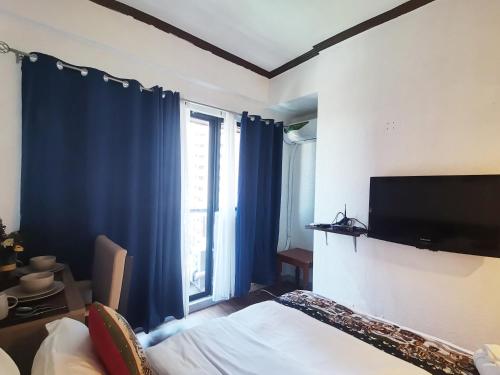 een slaapkamer met een bed en een flatscreen-tv bij warm makati in Manilla