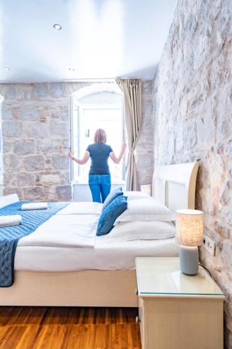 a woman is looking out of a window in a bedroom at Luxury Rooms Lucija and Luka in Split
