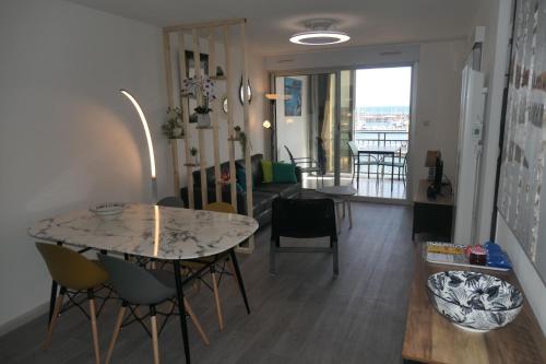 un salon avec une table et des chaises et un salon dans l'établissement Vue port et mer, centre-ville, au calme, garage, à Sète