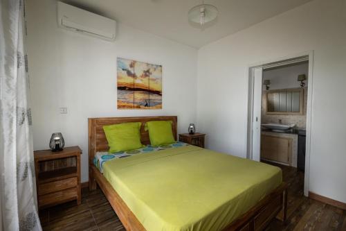 1 dormitorio con 1 cama grande con almohadas verdes en Les Villas 33, en Baie du Tombeau