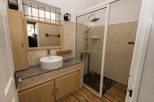 y baño con lavabo y ducha. en Les Villas 33, en Baie du Tombeau