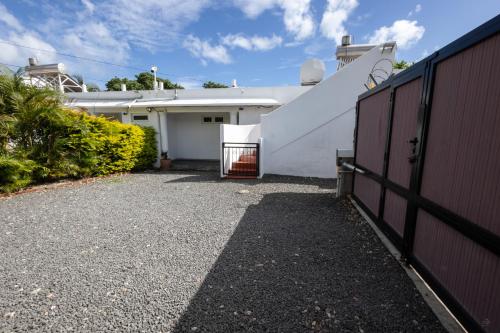a white house with a fence and a driveway at Les Villas 33 in Baie du Tombeau