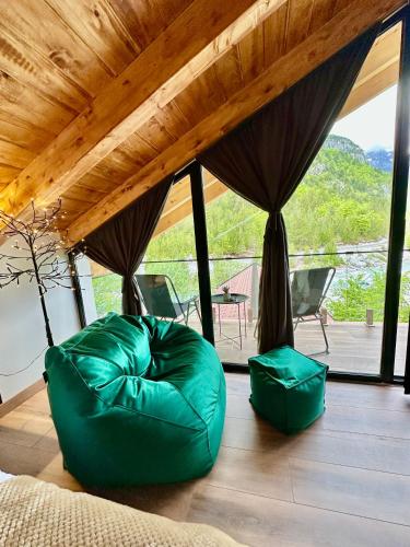 a living room with a green couch and a large window at Guesthouse Marashi in Theth