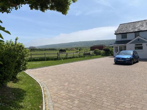 a blue car parked in a driveway next to a house at Tollgate Cottages Bed and Breakfast in Freshwater
