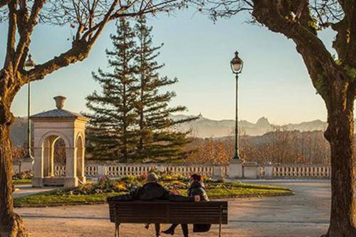 dos personas sentadas en un banco en un parque en Appartement calme et cosy, en Pau