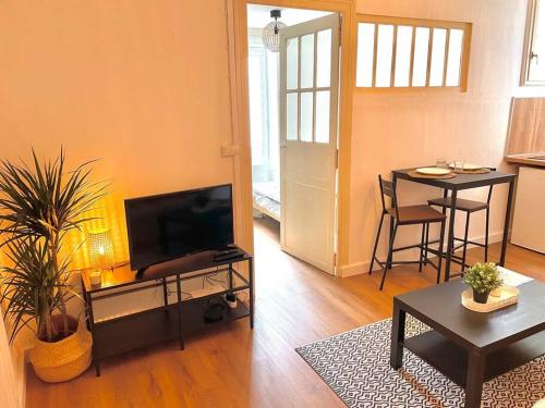 a living room with a flat screen tv and a table at Appartement calme et cosy in Pau