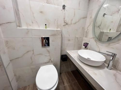 a white bathroom with a toilet and a sink at Hotel Lido in Athens