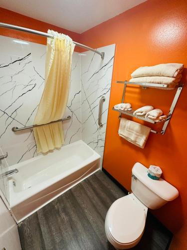a bathroom with a toilet and a shower and a tub at Amber Inn in Le Mars