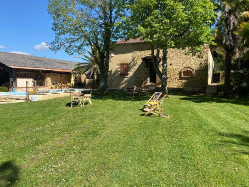 a yard with two chairs in front of a house at Maison Lacourrège in Urgosse