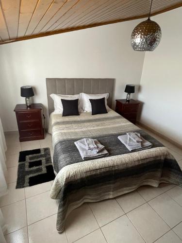 1 dormitorio con 1 cama grande y 2 mesitas de noche en Alojamento Amor de Mãe en São Teotónio