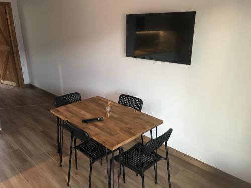 a wooden table with chairs and a television on a wall at Apartamenty MOGADOR in Szczytna