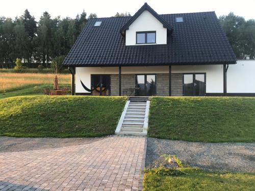 a small white house with a black roof at Apartamenty MOGADOR in Szczytna
