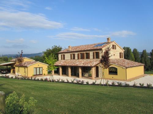 a large yellow house with a green lawn at Agriturismo La Vecchia Fonte in Castelbellino
