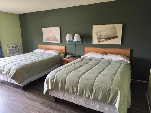 two beds in a bedroom with green walls at Harbor Lights Lodge in Kewaunee