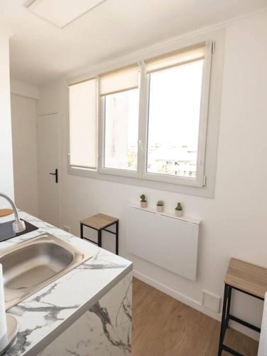 - une cuisine blanche avec évier et 2 fenêtres dans l'établissement Studio / 15min de la plage, à Fréjus