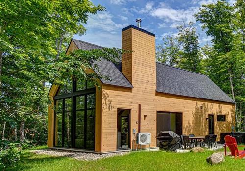 a large wooden house with a black roof at Nature's Paradis Chalets by Rcnt Chalets in Lac-Superieur