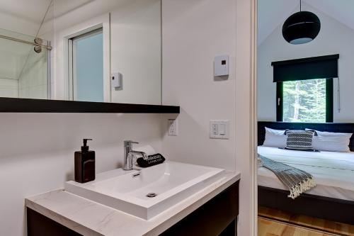 een badkamer met een wastafel en een bed bij Nature's Paradis 3 bedrooms by Rcnt Chalets in Lac-Superieur