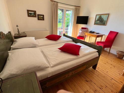 um quarto com 2 camas e almofadas vermelhas em Landhaus Strussnighof em Pörtschach am Wörthersee