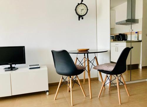 eine Küche mit 2 Stühlen, einem Tisch und einer Uhr in der Unterkunft Apartamento La Quinta in La Cala del Moral
