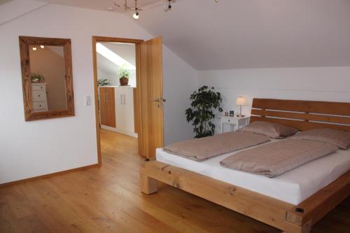 Schlafzimmer mit einem Bett mit einem Kopfteil aus Holz und einem Spiegel in der Unterkunft Ferienwohnung am Dreiseithof in Hauzenberg