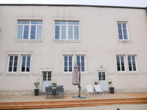 a patio with an umbrella and chairs in front of a building at Clos de la Providence Chambres d'hôtes, piscine et Spa in Nolay