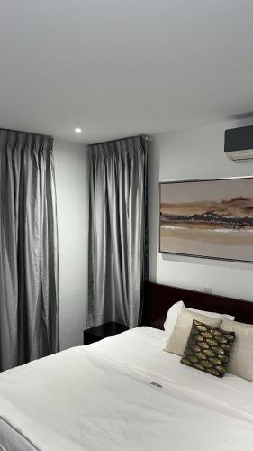 1 dormitorio con 1 cama blanca grande y cortinas en Nuben Court- Kumasi City en Kumasi