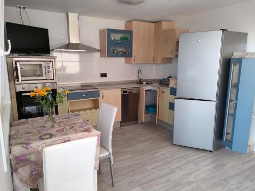 a kitchen with a table and a white refrigerator at Apartamento Loft A Estivada Bajo in Rosal