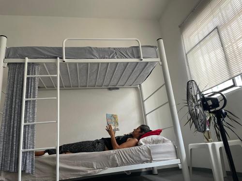 a woman laying on a bunk bed reading a book at Vive Alegria Hostel in Puerto Vallarta