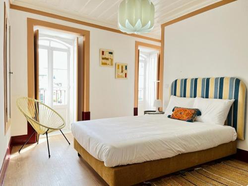 a bedroom with a large bed and a chair at Casa Rosa com AC in Coimbra