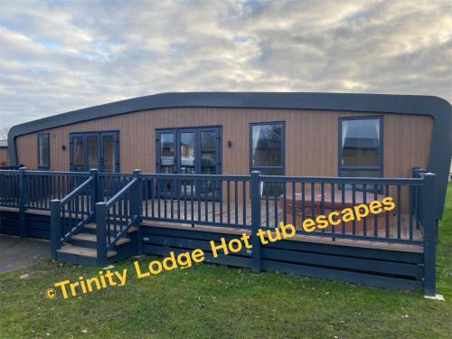 a small building with a sign that reads trinity lodge hot dog escapes at Trinity lodge hot tub escapes at Tattershall lakes in Tattershall