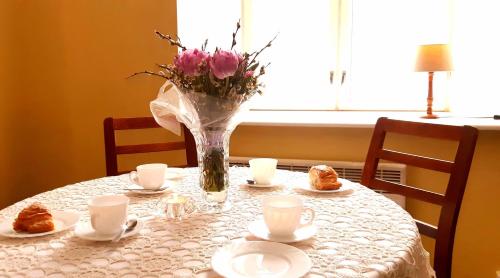 una mesa con un jarrón de flores y pasteles. en Pärnu-Jaagupi pastoraat, en Pärnu-Jaagupi