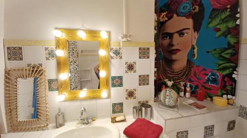 a bathroom with a sink and a mirror with a woman on the wall at MAISON DE CHARME AVEC COUR, proche rue des Teinturiers in Avignon