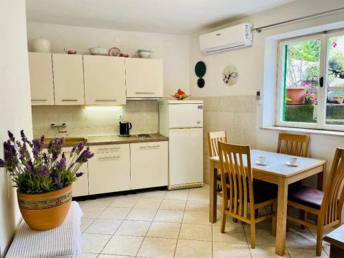a kitchen with white cabinets and a table and a vase with flowers at Apartments Villa Rosa in Split