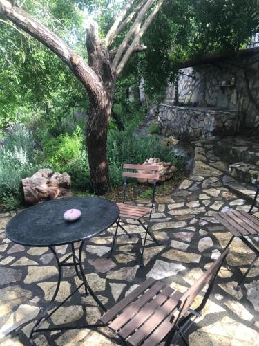 a picnic table and two chairs and a tree at Gourgiana Apartments in Andritsaina