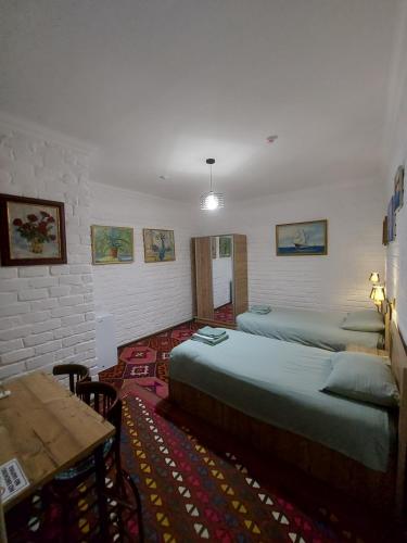 Cette chambre comprend 2 lits et une table. dans l'établissement MUSAVVIR, à Samarcande